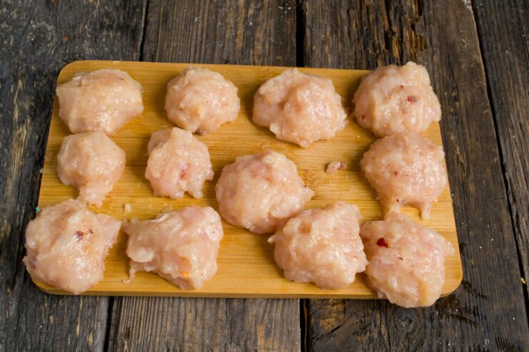 Shaping the Perfect Chicken Meatballs by Hand Small, raw chicken meatballs arranged on a cutting board.