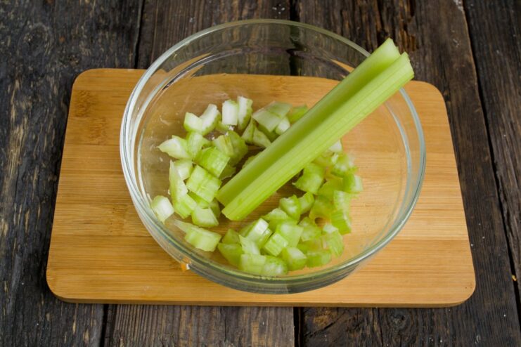 Adding Celery for Aromatic Depth Chopped celery being added to the pot with sautéed onions.