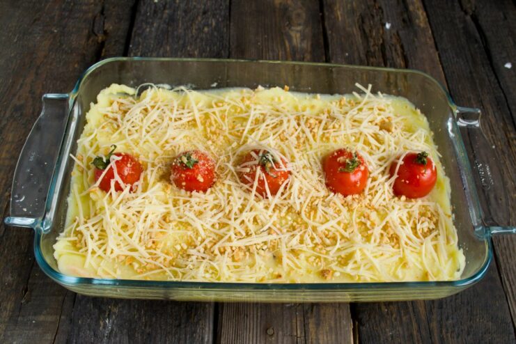 Grated cheese being sprinkled over the pie before it goes into the oven.