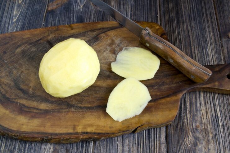 Step 1: Preparing the Potato for Slicing A peeled potato with one side sliced off to create a flat base for stability.
