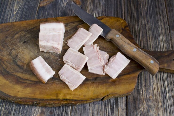 Step 2: Preparing the Ham Filling Thinly sliced pieces of ham on a cutting board, ready to be stuffed into the potato.