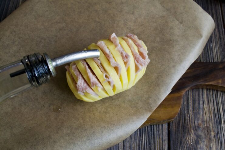 Step 4: Seasoning with Olive Oil Drizzling extra virgin olive oil over the ham-stuffed accordion potato.