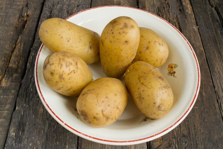 Step 1: Boiling potatoes until tender Whole potatoes boiling in a pot of water.