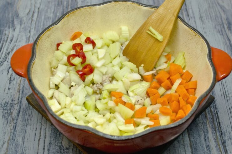 Building the Flavor Base with Sautéed Vegetables Sautéing chopped onion, carrot, celery, and chili with the seared chicken.