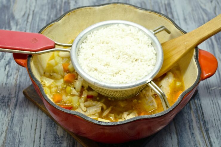 Incorporating the Rice into the Plov Base Adding a layer of rinsed long-grain white rice over the chicken and vegetables.