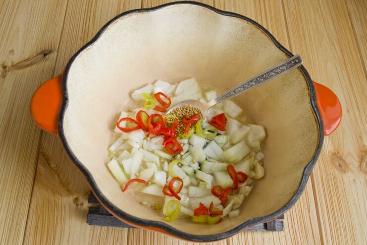 Adding Aromatics: Garlic and Chili for a Flavor Kick Minced garlic and sliced chili pepper added to the onions and spices in the pan.