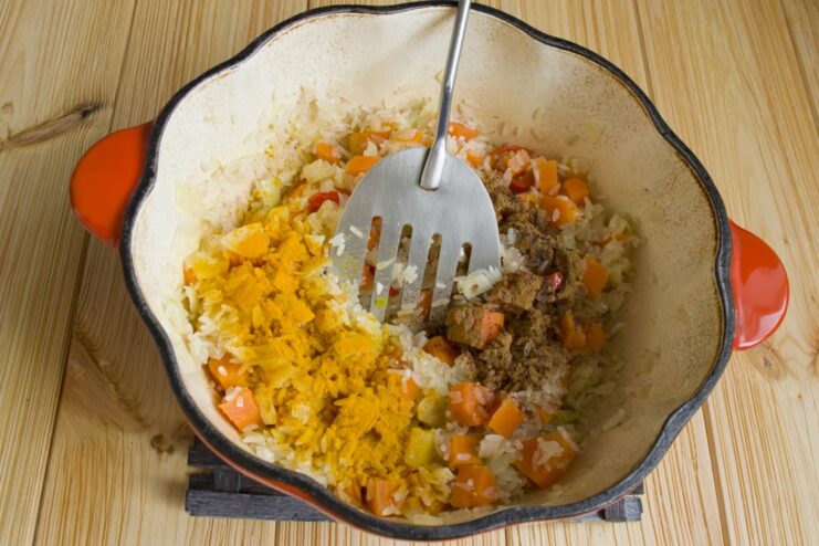 Simmering the Plov: Adding Spices and Water Spices and water being added to the rice and vegetable mixture in the pot.