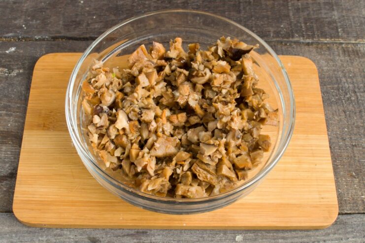 Preparing the mushrooms for the savory sauce Chopped salted mushrooms on a cutting board with a knife.