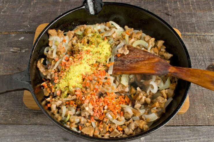 Building flavor: Sautéing onions, mushrooms, and carrots for the sauce A pan with sautéed onions, chopped mushrooms, and dried carrots being cooked.