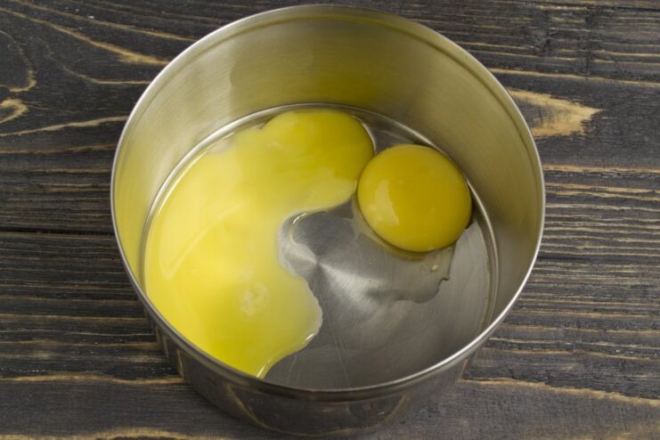 Separating Egg Yolks for the Fish Soufflé Two bright yellow egg yolks in a small white bowl, separated from the whites.