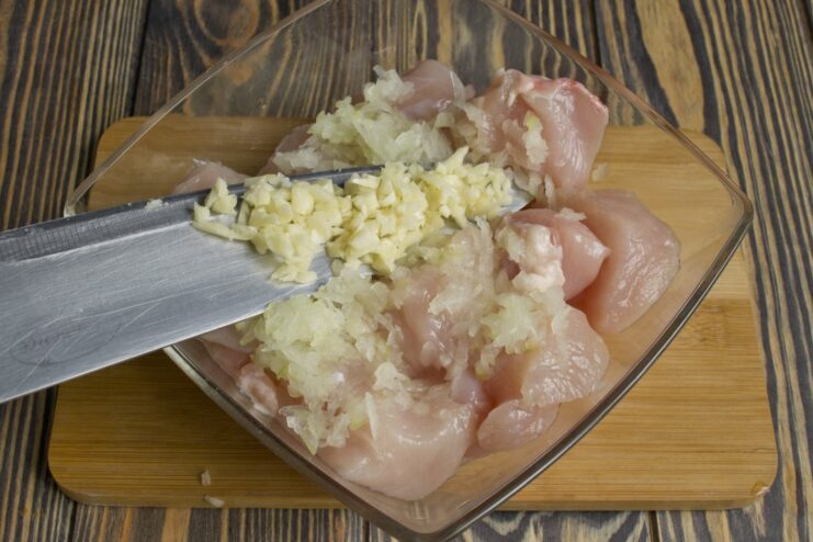 Adding Freshly Minced Garlic to the Marinade Close-up of minced garlic being added to the chicken.