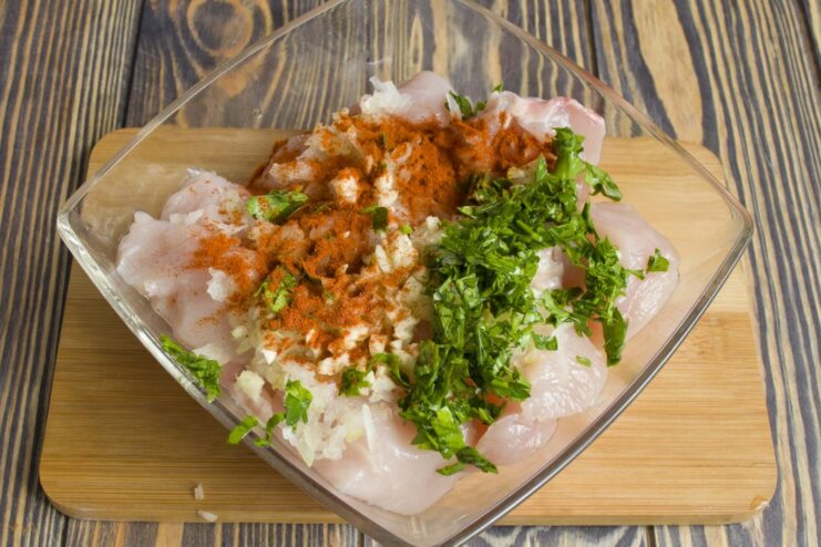 Seasoning Chicken with Paprika and Parsley Sweet paprika and chopped parsley being sprinkled over the chicken pieces.
