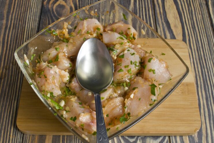 Mixing Chicken with Oil to Lock in Juices Vegetable oil being poured into the bowl with marinated chicken.