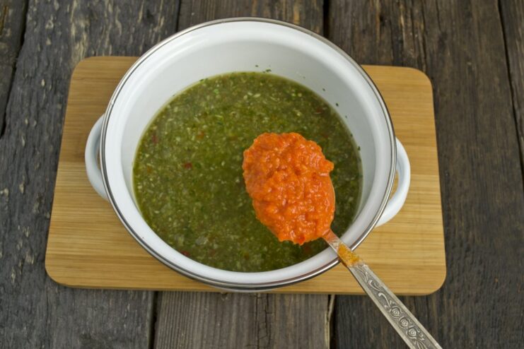 Enhancing the Marinade with Ketchup or Tomato Sauce A spoon adding ketchup to the vegetable and spice marinade mixture.