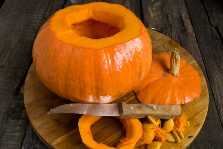 Preparing the Pumpkin Shell for Stuffing A person's hands scooping out seeds and pulp from a hollowed-out pumpkin.