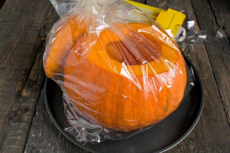 Pre-baking the Pumpkin to Soften It A hollowed-out pumpkin in a roasting bag, ready to be baked in the oven.