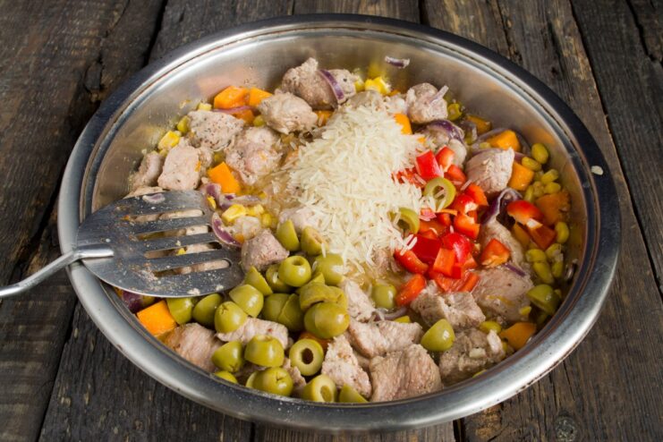 Completing the Filling with Rice and Olives Rice, olives, and peppers added to the pork and vegetable mix in the pan.