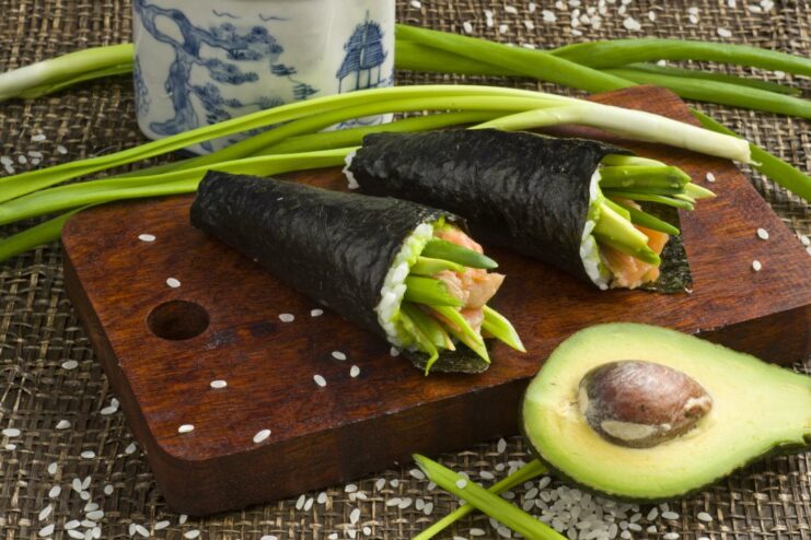 A plate of freshly made temaki sushi hand rolls with avocado and trout.