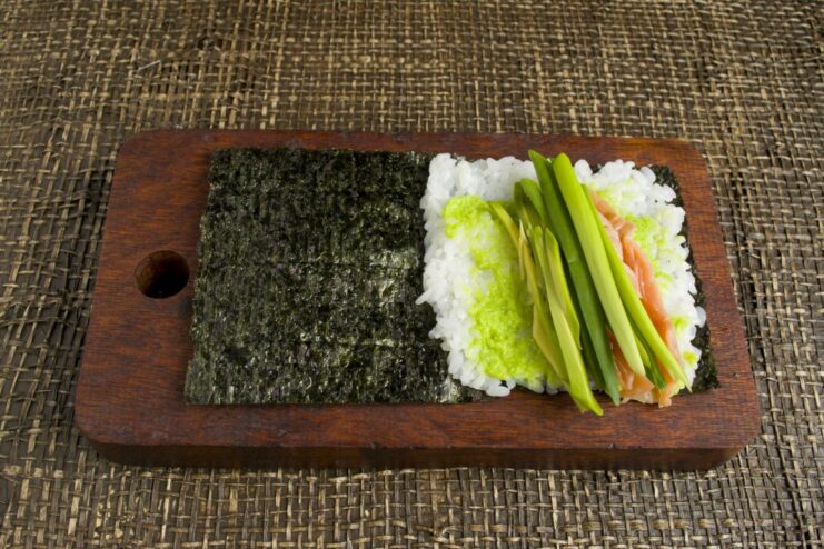 Completing the Filling with Fresh Scallions Fresh green scallion sprigs being added to the temaki fillings.