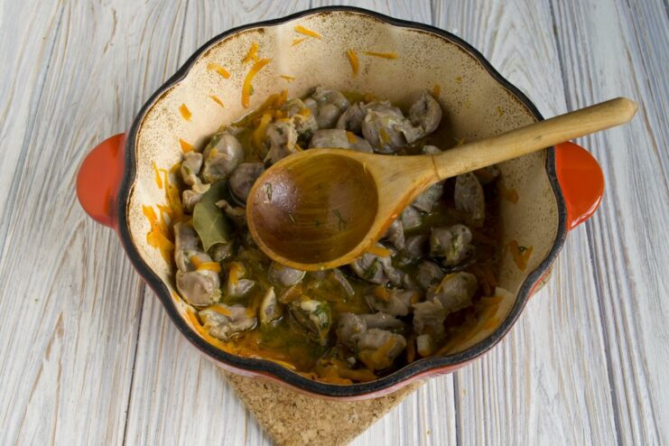 Slowly stewing the chicken gizzards until they become tender and flavorful. Chicken gizzards simmering in a rich broth in a Dutch oven.