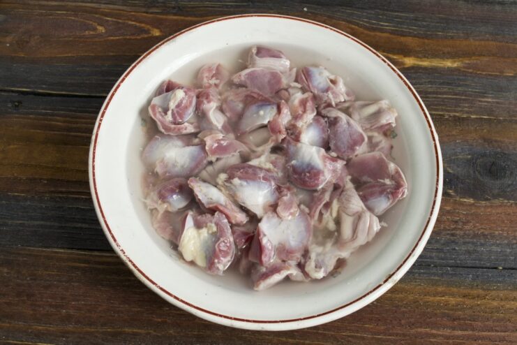 Step 1: Preparing the Chicken Gizzards for Cooking Raw, cleaned chicken gizzards in a white bowl, being prepared for the recipe.