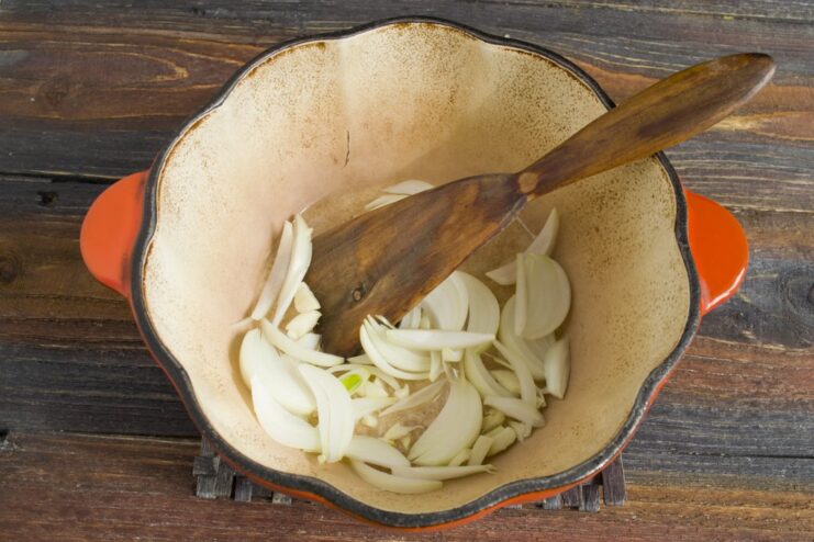 Building Flavor by Sautéing Onions Until Golden Finely chopped onions being sautéed in a pan with hot oil until translucent.
