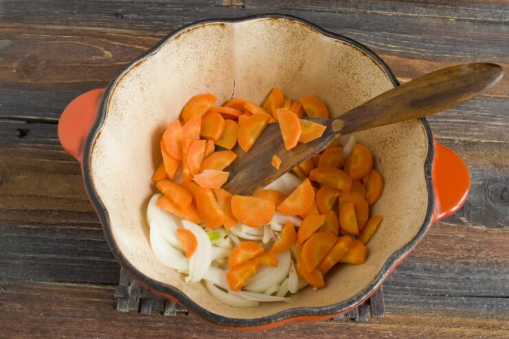 Adding Carrots to the Onions for a Sweet and Savory Base Diced carrots and onions being sautéed together in a pan to create a flavorful base.