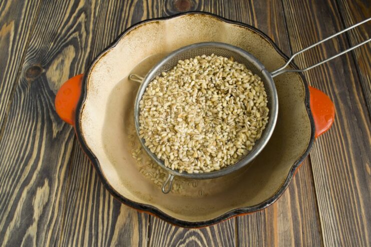 Cooking Pearl Barley in a Dutch Oven Pearl barley cooking in water in a black Dutch oven.