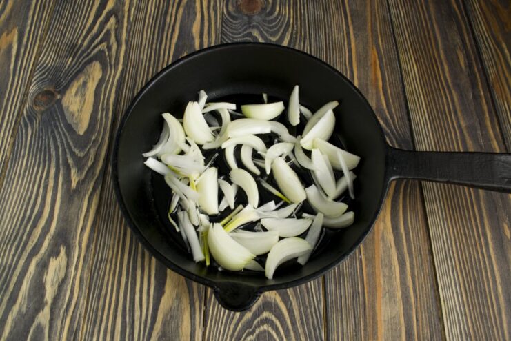 Sautéing Chopped Onions in a Pan Chopped onions being sautéed in a frying pan with a wooden spatula.