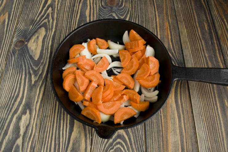 Adding Carrots to Sautéed Onions Coarsely chopped carrots added to the frying pan with sautéed onions.