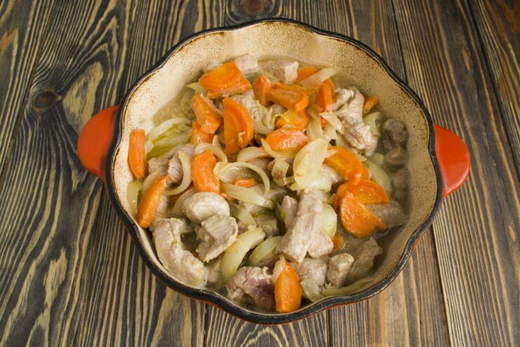 Combining Meat and Vegetables with Pearl Barley Sautéed pork and vegetables being added to the pot of cooking pearl barley.