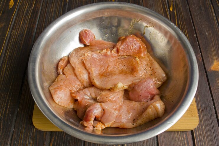 Marinating the pork with spices enhances its flavor Pork slices being seasoned with salt and spices before marinating.