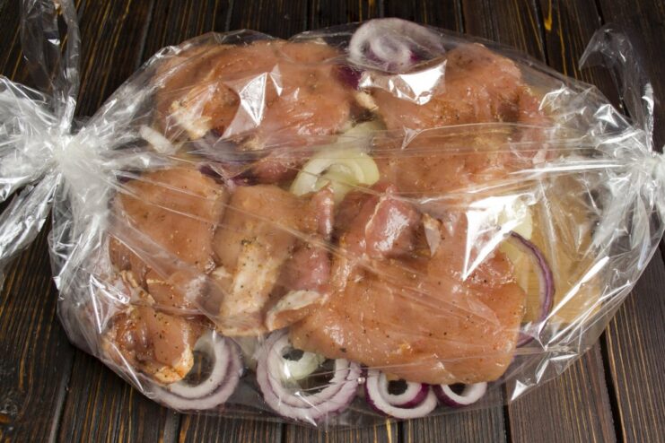 Using a baking sleeve keeps the meat moist and tender Marinated pork placed on a bed of onions inside a clear baking sleeve.