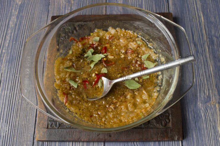 Mixing ground spices into the marinade in a small bowl.