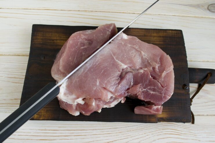 Cubing Lean Pork for the Patties Close-up of lean pork being diced into small cubes on a cutting board.