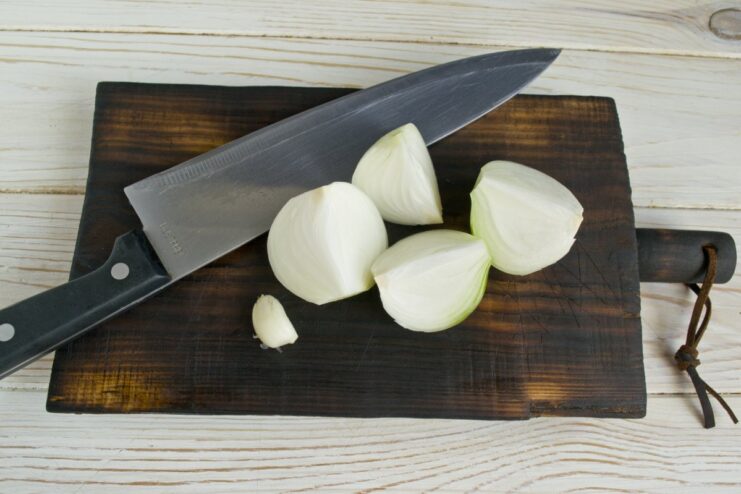 Chopping an Onion for the Meat Mixture A yellow onion being cut into several large pieces before processing.