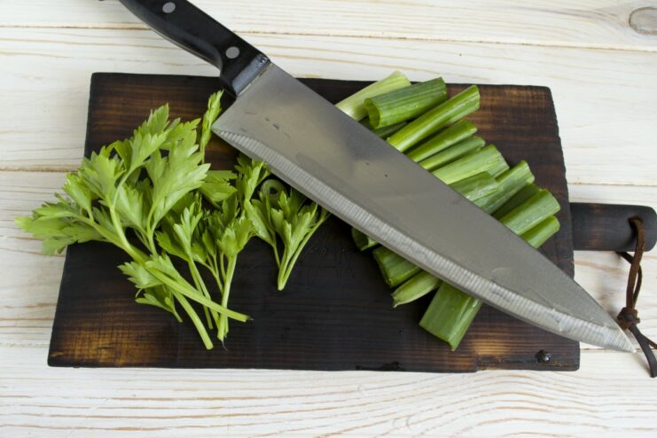 Finely Chopping Fresh Herbs A bunch of fresh green onions and parsley being finely chopped on a cutting board.