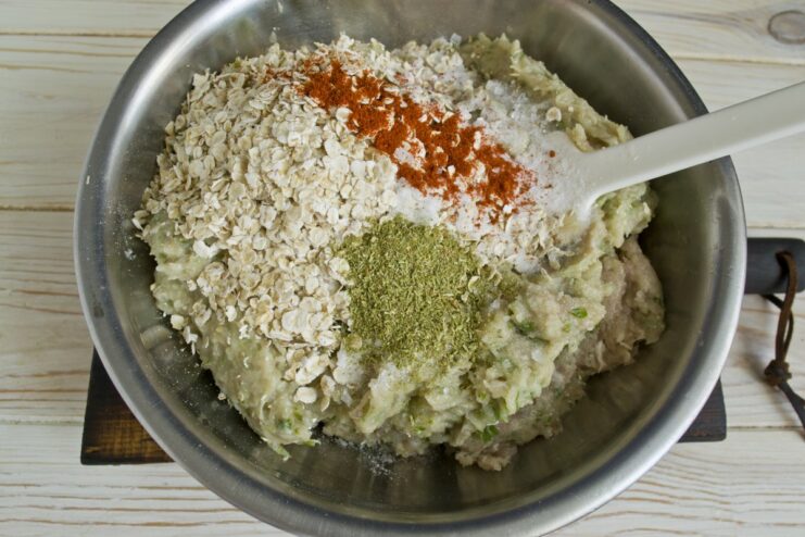 Seasoning the Ground Meat Mixture A bowl of ground meat mixture with rolled oats, paprika, and other seasonings being added.
