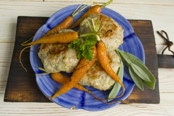 Serving the Hot and Juicy Baked Meat Patties A serving of freshly baked meat patties with carrots, garnished with fresh herbs.