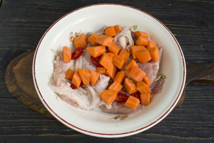 Preparing Carrots for the Chicken and Potato Bake Diced carrots being added to a bowl with chicken and peppers.