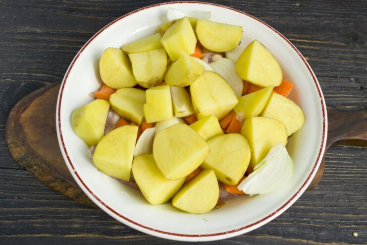 Chopping Potatoes for a Hearty Chicken Bake Large chunks of potato being added to the bowl with chicken and other vegetables.