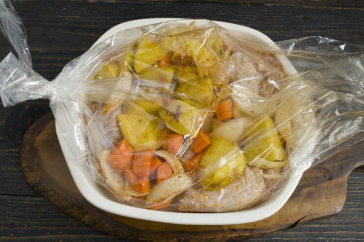 Getting the Roasting Bag Ready for the Oven A sealed roasting bag filled with chicken and vegetables placed in a glass baking dish.