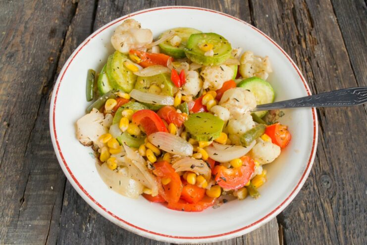 Vegetables roasting on a baking sheet to golden-brown perfection. A baking sheet with a colorful mix of seasoned vegetables, ready to go into the oven.