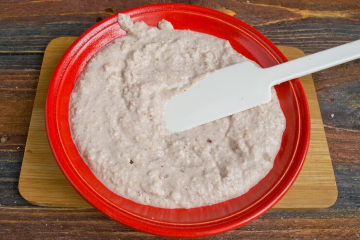 Create a bed of the creamy bazhe sauce on the plate before adding the vegetables. A layer of creamy bazhe sauce being spread on a white plate.
