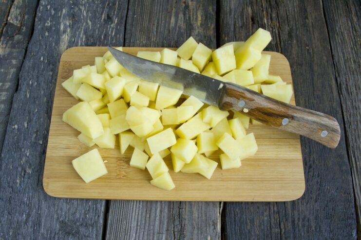 Frying potatoes until half-cooked for the Ajapsandali base Diced potatoes being fried in a pan until golden brown.