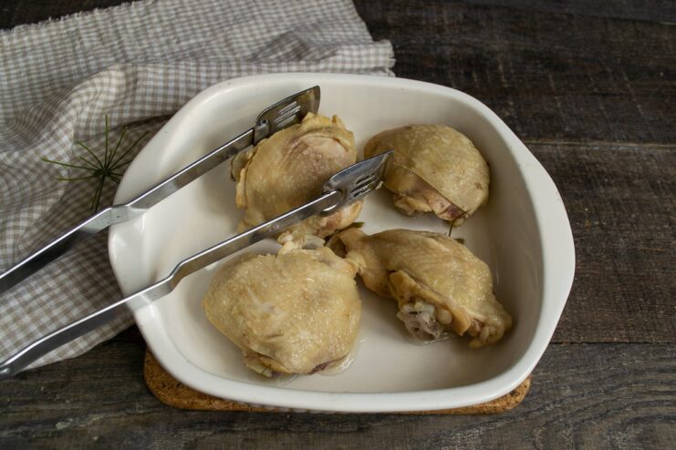 Arranging the Cooked Chicken in a Baking Dish Pieces of boiled chicken being placed in a greased glass baking dish.