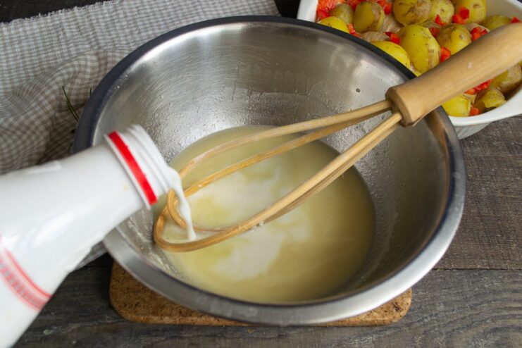 Adding Cream to the Sauce for Richness Cream being poured into the flour and broth mixture in a white bowl.