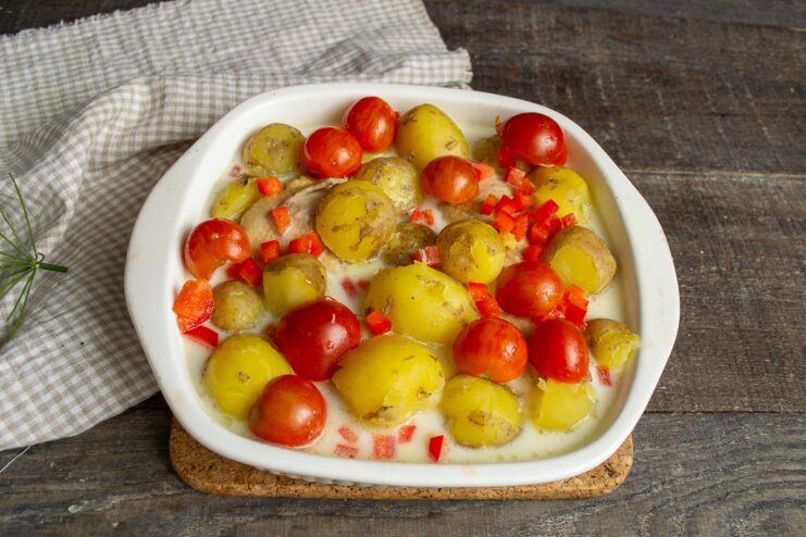 Adding Whole Cherry Tomatoes for a Burst of Flavor Whole cherry tomatoes being added to the chicken and potatoes covered in sauce.