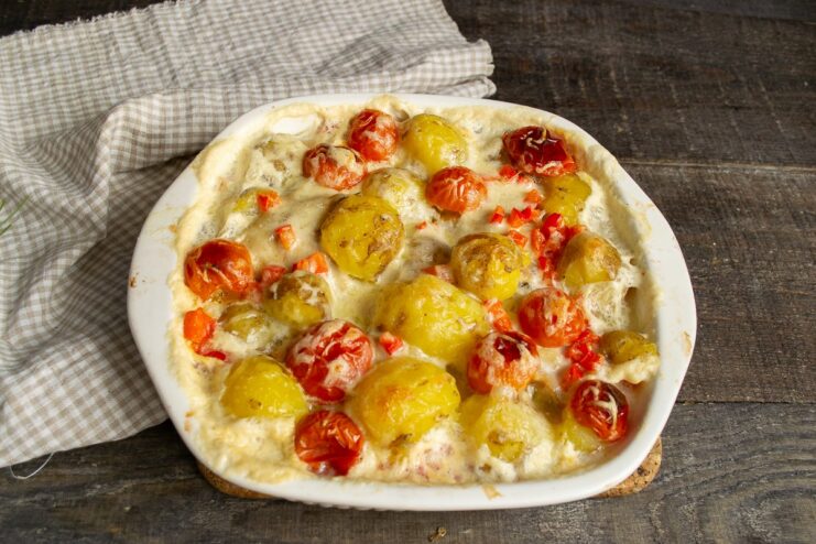 Baking the Dish Until Golden and Bubbly The baking dish with chicken and potatoes is placed in a hot oven.