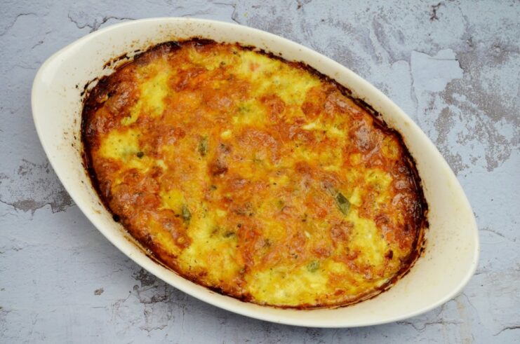 The fish casserole, covered with foil, baking in an oven.